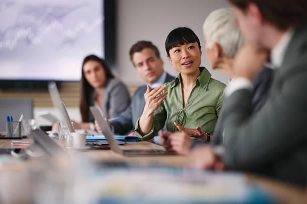 An executive leading a boardroom discussion with senior colleagues in Bangkok
