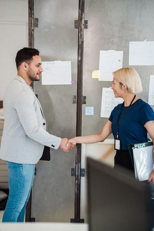A hiring manager and a newly placed executive shaking hands in a Bangkok office